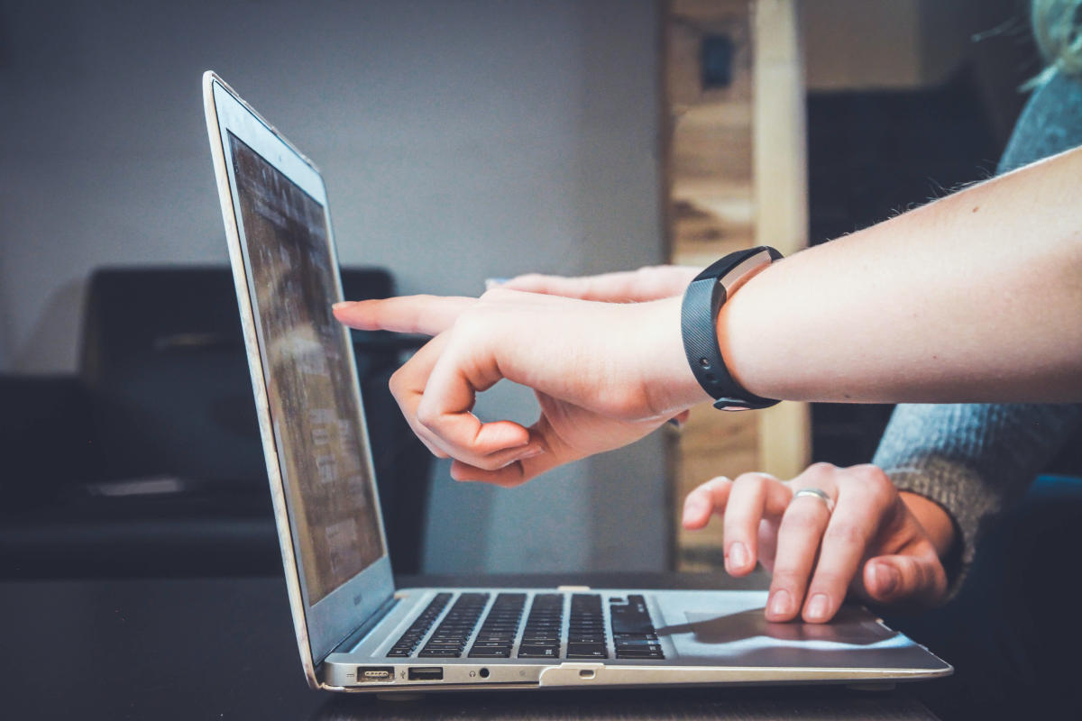 Hände zeigen auf Laptop