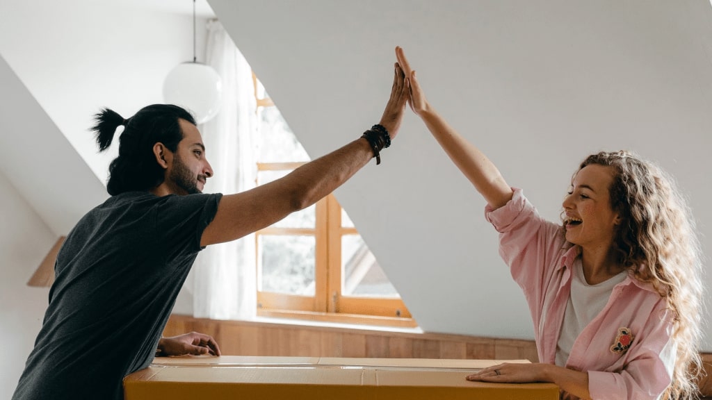 Zwei Tauschpartner geben sich ein High Five über einem Umzugskarton